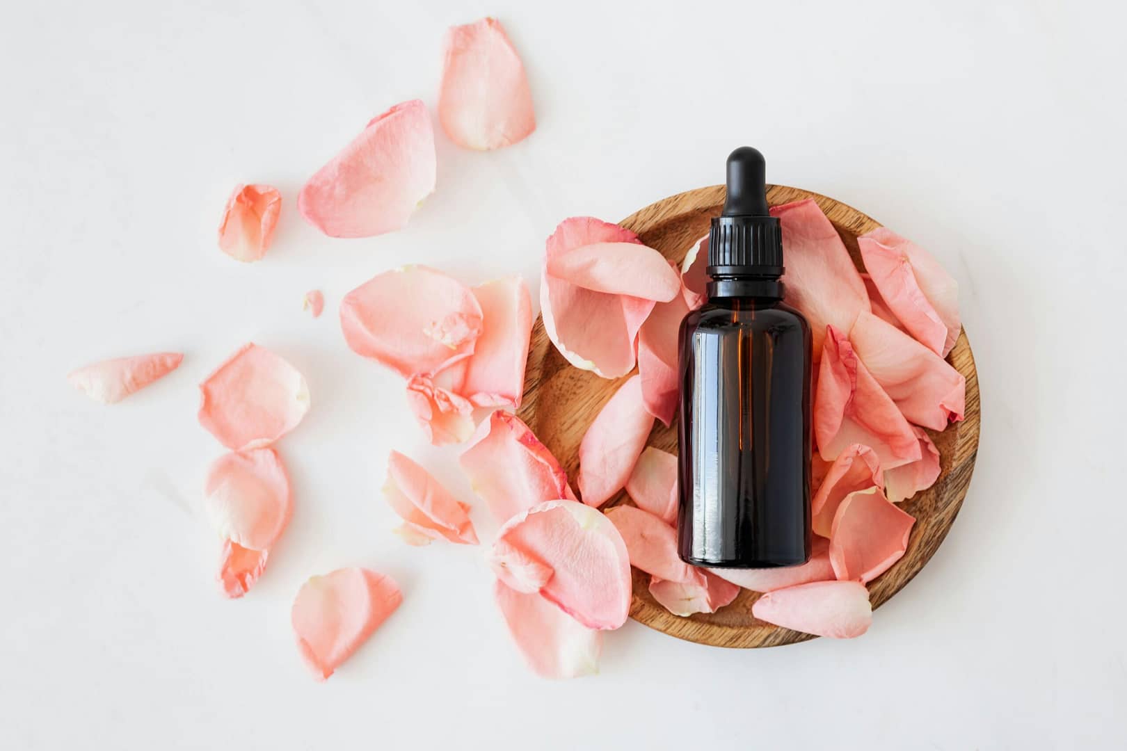 bottle of essential oils for relaxation and sleep on pink rose petals